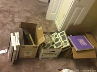 Boxes on carpet containing various photo frames and albums.