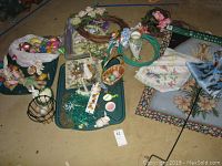 Photo showing assortment of spring and Easter decorations including plastic eggs, wreaths, baskets, fabric pieces, and ceramic vase arranged on floor.