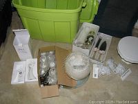 Photo showing green storage bin, multiple boxes with various decorative wedding items including tealights, glass holders, faux diamond beads, and cake plate.
