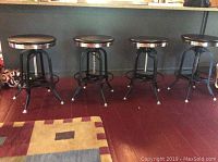 Four stools lined up against wall under counter
