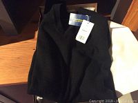 Black cashmere V neck sweater folded in box with tags attached.