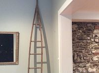 Full view of tall wooden apple picking ladder leaning against wall