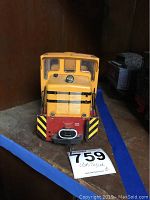 Front view showing yellow body with black stripes, red front with coupling hook, and clear windows in cab
