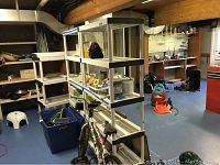 Three white plastic shelving units, each with four shelves plus top, located in a basement. Shelves are slatted and measure approximately 35x18x72 inches.