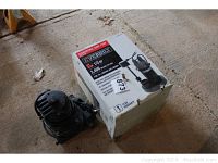 Everbilt submersible sump pump next to its original box on concrete floor, showing the pump and packaging with visible model info.