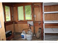 View of propane heater installed or standing with propane tanks nearby in garage with windows and wooden walls