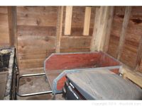 Wood and aluminum flower cart with metal handle and wooden base inside a wooden shed, visible wear and minor dirt accumulation
