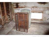 Chicken coop with slatted wood construction, showing pinholes and chipping paint in barn setting