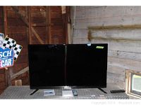 Front view of the Westinghouse 49 inch flat panel TV showing the screen, remote, and some documentation on a metallic surface.