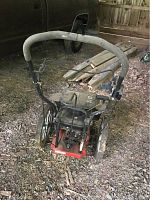Front angle view of the Troy-Bilt mower showing handlebar, control cables, and cutting blade housing.