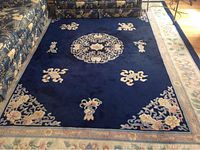 Full view of the main indigo rug with floral and Chinese symbol patterns, next to a matching runner rug.