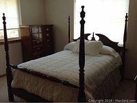 Full bedroom view showing cherry four-poster bed with bedding and highboy dresser in corner