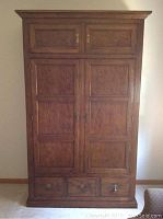 Front view of walnut armoire with two upper doors and three lower drawers