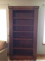 Front view showing tall cabinet with six shelves, fluted columns and crown molding top and bottom.