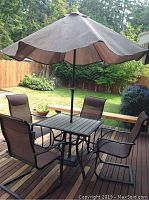 Full view of square wood-slat table, four sling chairs, umbrella and base on deck