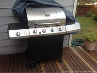 Char-Broil Classic propane gas grill with cover, showing stainless steel front panel with control knobs and wheels.