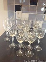 Photo showing 16 pieces of Waterford Crystal Cullen stemware, including red wine, white wine glasses and champagne flutes arranged on a counter.