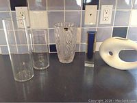 Group photo showing all five vases: two clear glass vases, one lead crystal vase, one blue glass bud vase, and one white ceramic abstract vase.