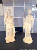 Marble statues of Athena and Aphrodite shown standing next to each other against a tiled background