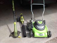 Lawn mower, blower and weed whacker side by side showing size and green colors