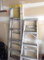 5-foot Werner fiberglass and 6-foot aluminum step ladders side by side against the garage wall.