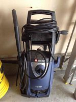 Front view showing the power washer's main body, power cord wrapped around the top handle, and the attached spray wand.