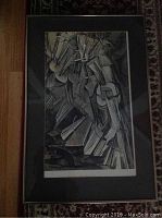 Framed print showing the full artwork with geometric, cubist figure descending stairs, black frame and gray matting visible.