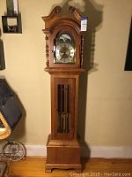 Full front view of the clock showing overall case, dial, weights and base