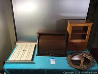 View of all items on table: small wooden cabinet, white rack, wooden roll-top desk, two round mirrors