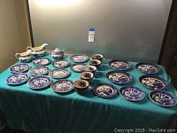 Wide view of complete Blue Willow pattern china set laid out on teal cloth