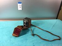 Front and side angled view of Ricohflex Model VII camera in leather case with strap extended.