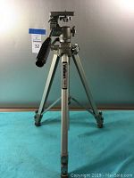 Full view of Velbon VGB3 tripod standing on blue surface against neutral background