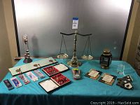 Photo of the entire lot on blue tablecloth including balance scale, lantern, temperature gauge, collectibles, and plaques