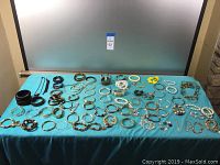 Full overview of collection spread on blue cloth, showing a wide selection of bracelets and sets including multiple pairs and styles.