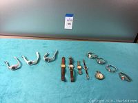 Full view on a teal surface showing fifteen watches with different bands and styles, including one pocket watch.