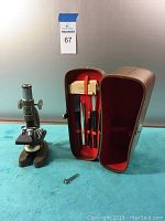 Empire vintage microscope with case and accessories laid on blue cloth.