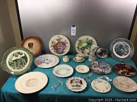 Full view of decorative plates arranged on a table with plate stands and a figurine.