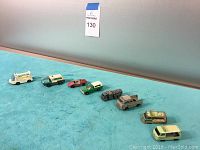 Overview of the eight vintage toy vehicles arranged in a row on a blue towel showing varying colors and types