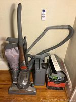 Full view of Kirby Sentria vacuum cleaner upright model with hose and attachments beside it, cord visible, and a carpet shampoo system box.