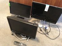 Three screens: two computer monitors and one Sylvania small TV, all with their respective cables and remote for the TV.
