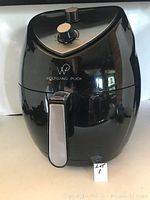 Front view of the black Wolfgang Puck air fryer with two control knobs and stainless steel handle on basket.
