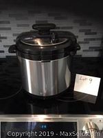 Front and side views of a Wolfgang Puck pressure cooker in black stainless steel with an 8-liter capacity.