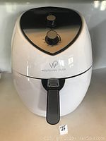 Front view of Wolfgang Puck white air fryer showing control knobs and logo.