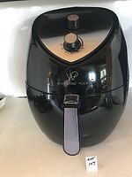 Front view of the Wolfgang Puck black air fryer with logo, two control knobs, and pull-out basket handle.