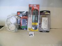 Image showing four electronic items including white Sony headphones, HDMI splitter, RCA remote in packaging, and a 25 ft line cord cable in packaging.
