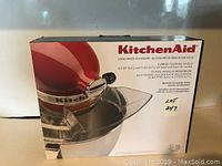 Front view of boxed KitchenAid pouring shield accessory for stand mixers.