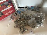 Overview of assorted kitchen and bath hardware items laid out showing hinges, towel rings, and door knob in packages.