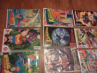 Photo showing a spread of 9 comics including Supergirl and Superman titles, all bagged and boarded, laid out on a wooden surface.