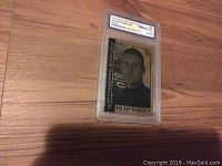 Photo of the 2004 Ben Roethlisberger gold rookie card graded mint 10 by WCG, showing the full card in its protective case on wooden floor.