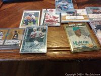 Front photo of 9 signed hockey and baseball cards on table, some cards in protective clear sleeves. Visible player images and autographs.